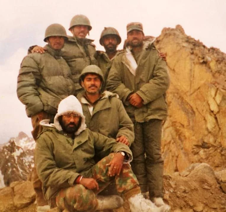 Army personnel together in a rocky mountain setting.